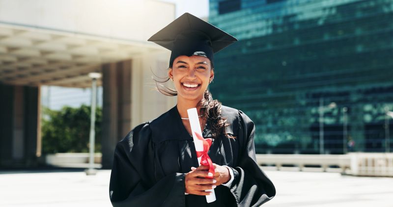 Smiling graduate holding diploma outdoors